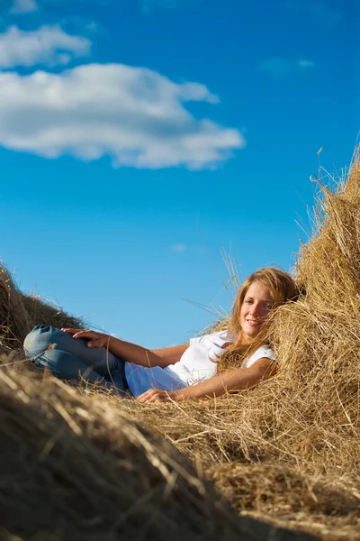 Menina descansando sobre palha fresca — Fotografia de Stock