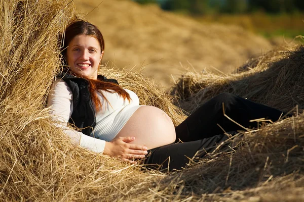 Těhotná dívka na seno — Stock fotografie