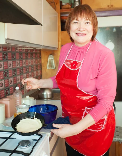 Mature woman bakes pancakes — Stock Photo, Image