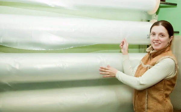 Flicka väljer polyeten på folie rulle — Stockfoto