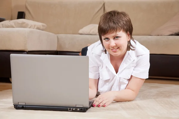Женщина лежит на полу и использует ноутбук — стоковое фото