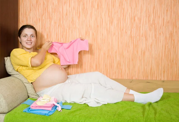 Pregnant woman with baby's clothe — Stock Photo, Image