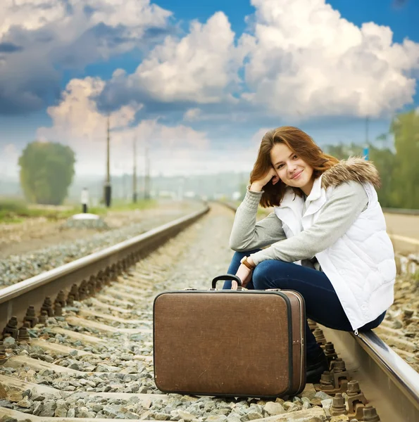 Девушка на железной дороге с чемоданом — стоковое фото