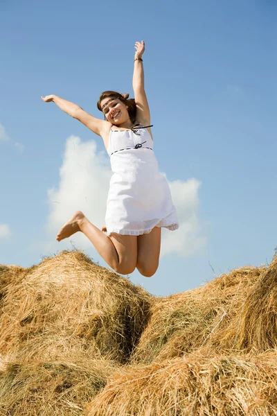 Jumping girl over hay — Stock Photo, Image