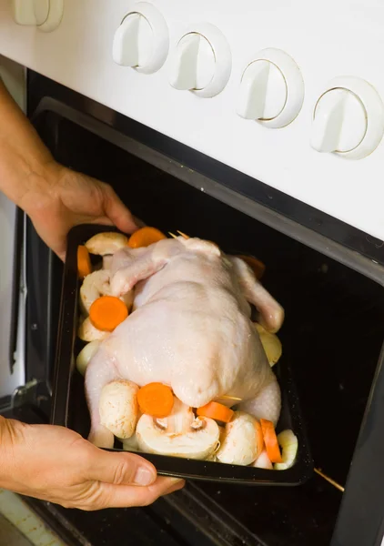 Mãos femininas colocando frango no forno — Fotografia de Stock