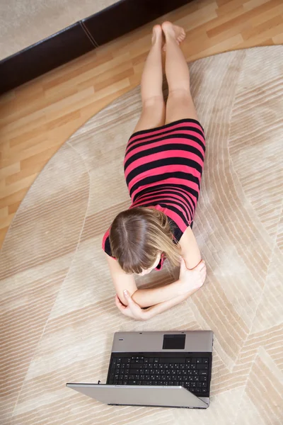 Ragazza sdraiata sul pavimento e utilizzando il computer portatile — Foto Stock