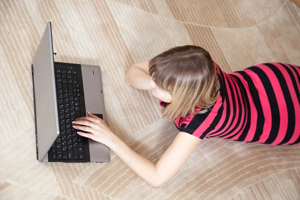 女孩躺在地板上和使用的便携式计算机 — 图库照片