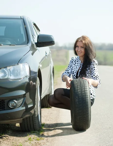 Mujer cambiando la rueda del coche — Foto de Stock