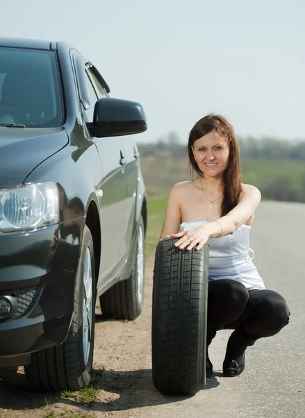 Жінка змінює автомобільне колесо — стокове фото