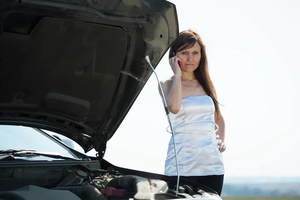 Kvinnan ringer genom mobil nära trasiga bil — Stockfoto