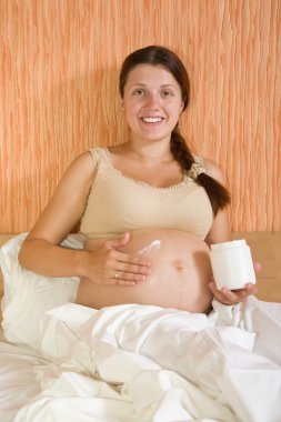 Pregnant woman rubs cream clipart