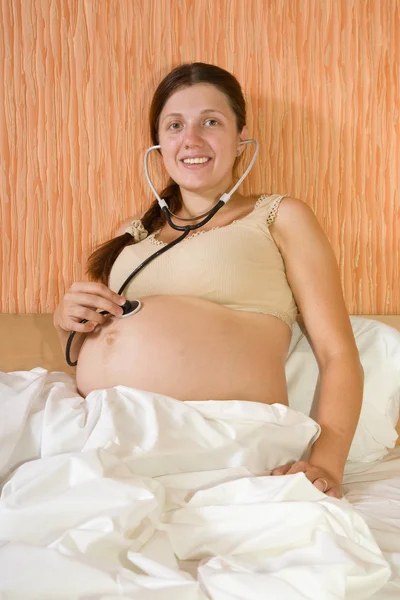 Pregnant woman listens her belly — Stock Photo, Image