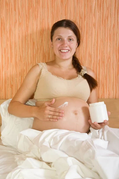 Беременная женщина протирает крем — стоковое фото