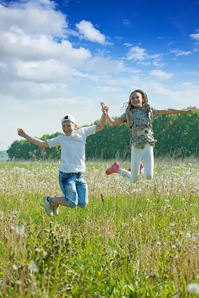 Garçon et fille sautant à prairie — Photo