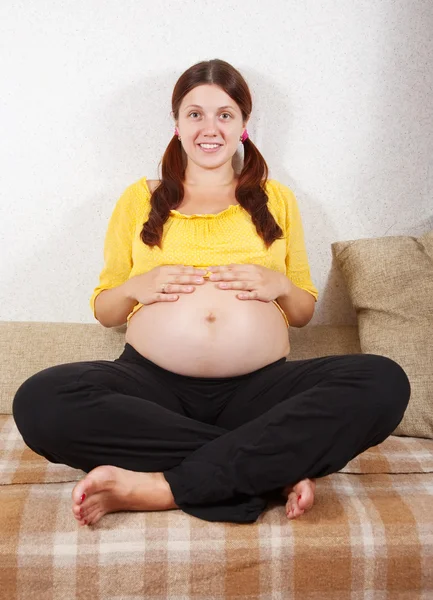 妊娠中の女性はソファに座って — ストック写真