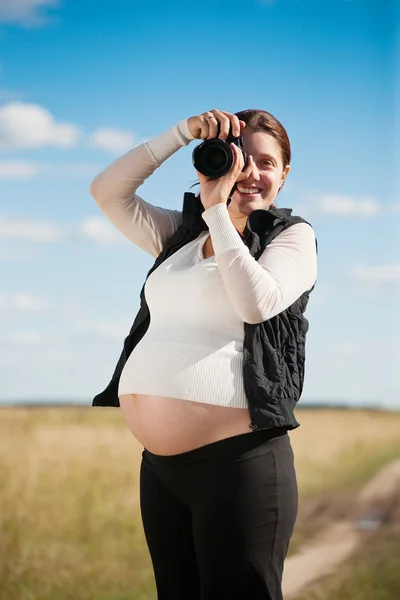 Беременная женщина с камерой — стоковое фото