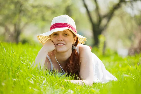Meisje in hoed liggen op gras — Stockfoto