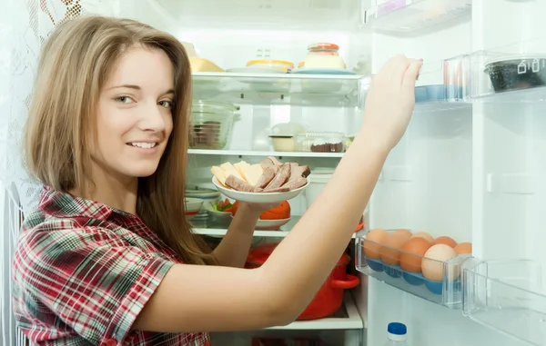 Flicka sättande mellanmål i kylskåp — Stockfoto