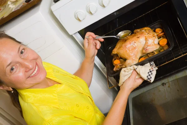Женщина жарит фаршированную курицу — стоковое фото