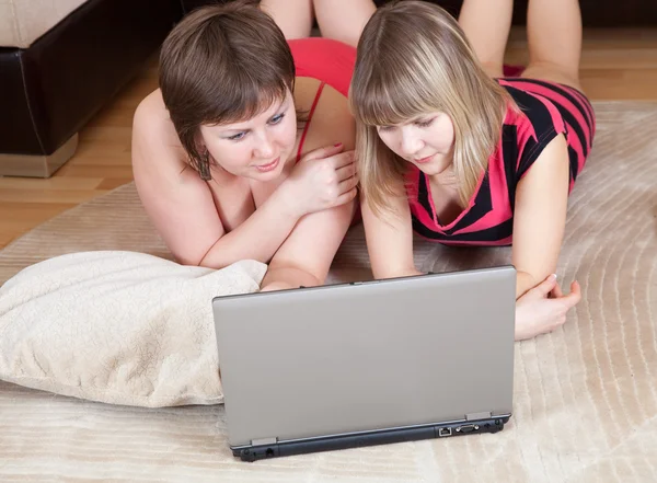 Девочки, лежащие на полу и пользующиеся ноутбуком — стоковое фото