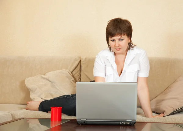 Žena pracující s přenosným počítačem v domě — Stock fotografie