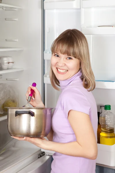 Γυναίκα που τρώει από το τηγάνι κοντά σε ψυγείο — Φωτογραφία Αρχείου