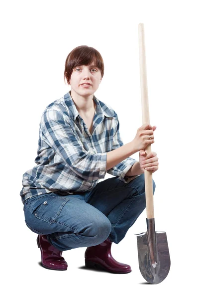 Woman sits with spade over white — Stock Photo, Image