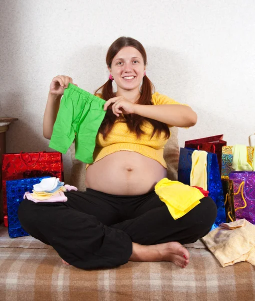 Pregnant woman with babies clothes — Stock Photo, Image