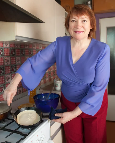 Volwassen vrouw bakt pannenkoeken — Stockfoto