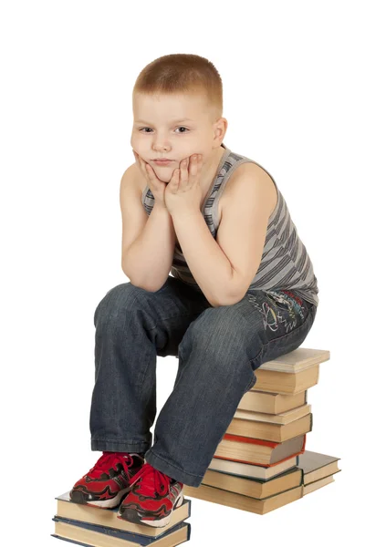 Kleine jongen zittend op zijn hoofd in zijn handen boeken — Stockfoto