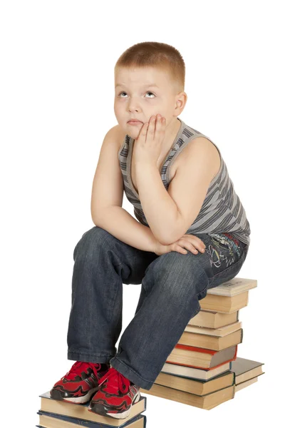 Ragazzo seduto sui libri della sua testa in mano — Foto Stock