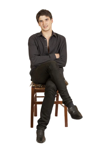 En ung man sitter på en stol — Stockfoto