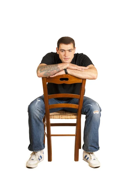 Hezký mladý muž sedí na židli — Stock fotografie