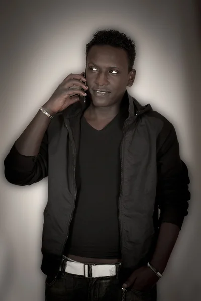 The dark-skinned young man with a mobile phone — Stockfoto