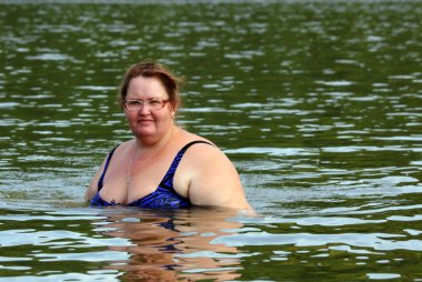 Plump woman bath in river clipart
