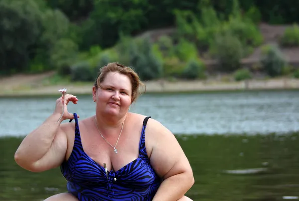 Пухнаста жінка сидить біля річки — стокове фото