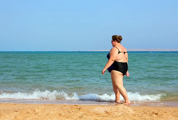 Överviktig kvinna gå på stranden — Stockfoto