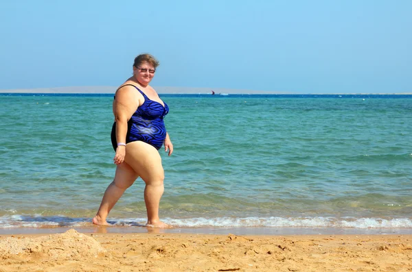 Overweight woman walking on beach — Stock Photo, Image
