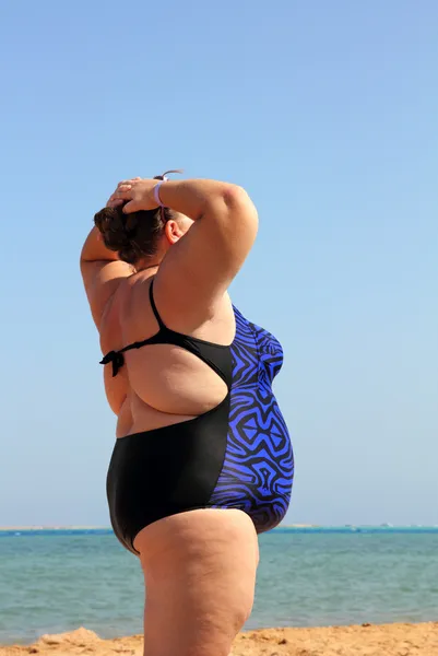 Overweight woman on beach with hands up — Stock Photo, Image