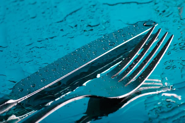 Forchetta e coltello sotto l'acqua blu — Foto Stock