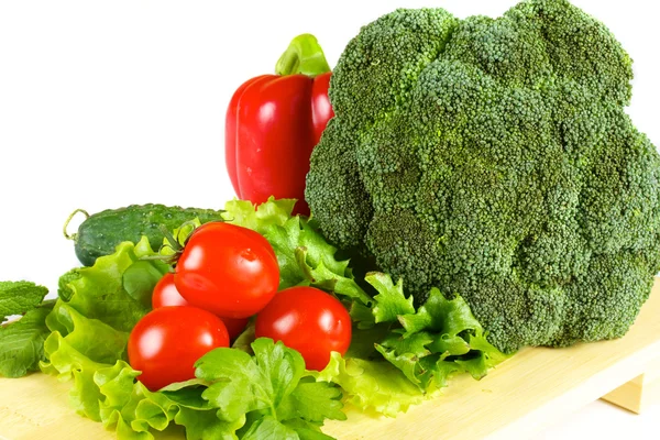 Friska och saftiga grönsaker på trä plattan isolerad — Stockfoto