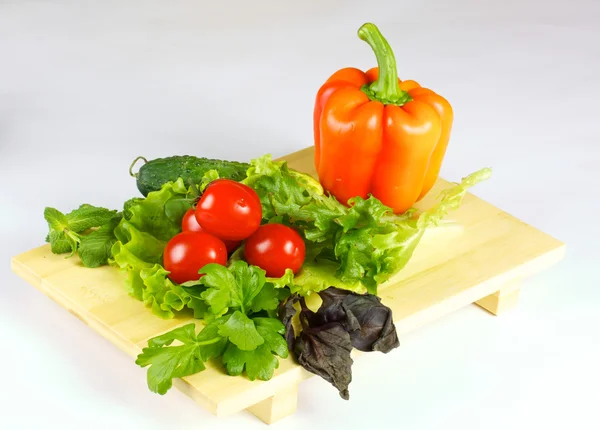 Свежие и сочные овощи на деревянной пластине изолированы — стоковое фото