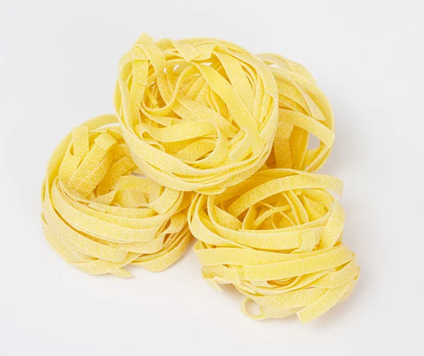Купа сирих сухих макаронних виробів на білому тлі — стокове фото