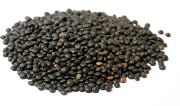 Heap de lentilha preta isolada em branco — Fotografia de Stock