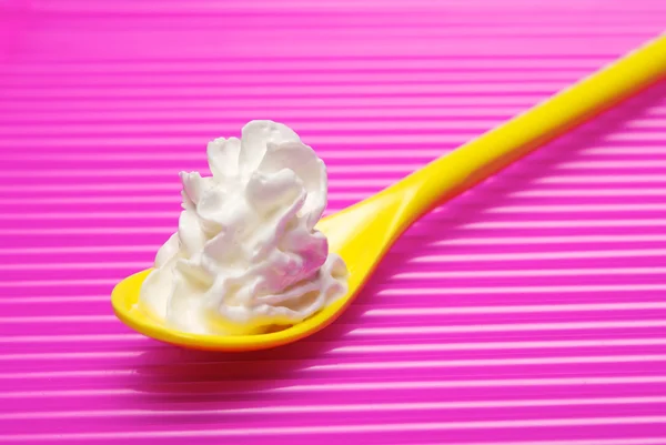 Yellow spoon and portion of whipped cream — Stock Photo, Image