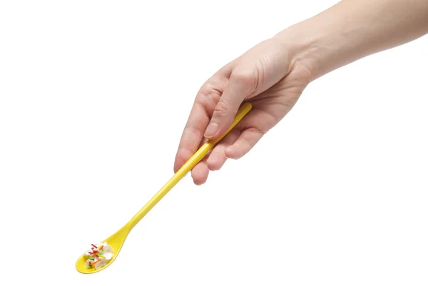 Hand holding a teaspoon full of cream — Stock Photo, Image