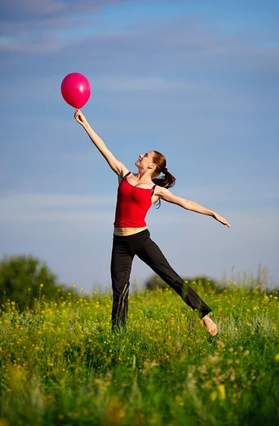 Frau springt mit rotem Luftballon — Stockfoto