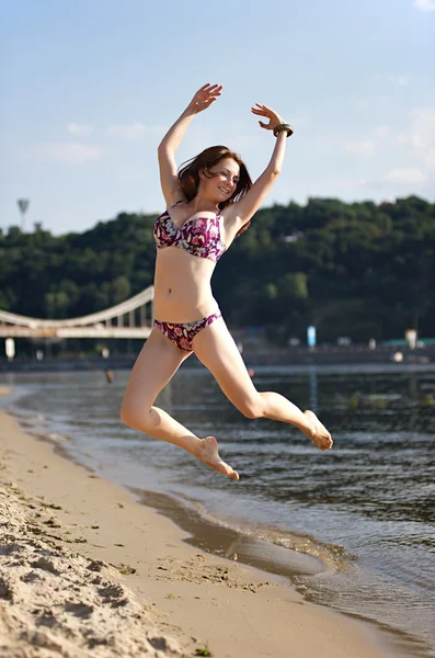Femme sautant sur la plage de la rivière — Photo