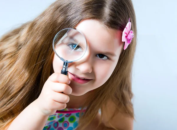 Little girl looking through a magnifying glass — Stock Photo, Image