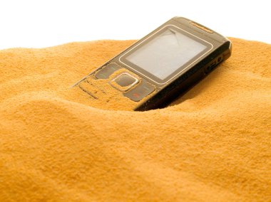 Mobile phone in sand isolated on white background. clipart